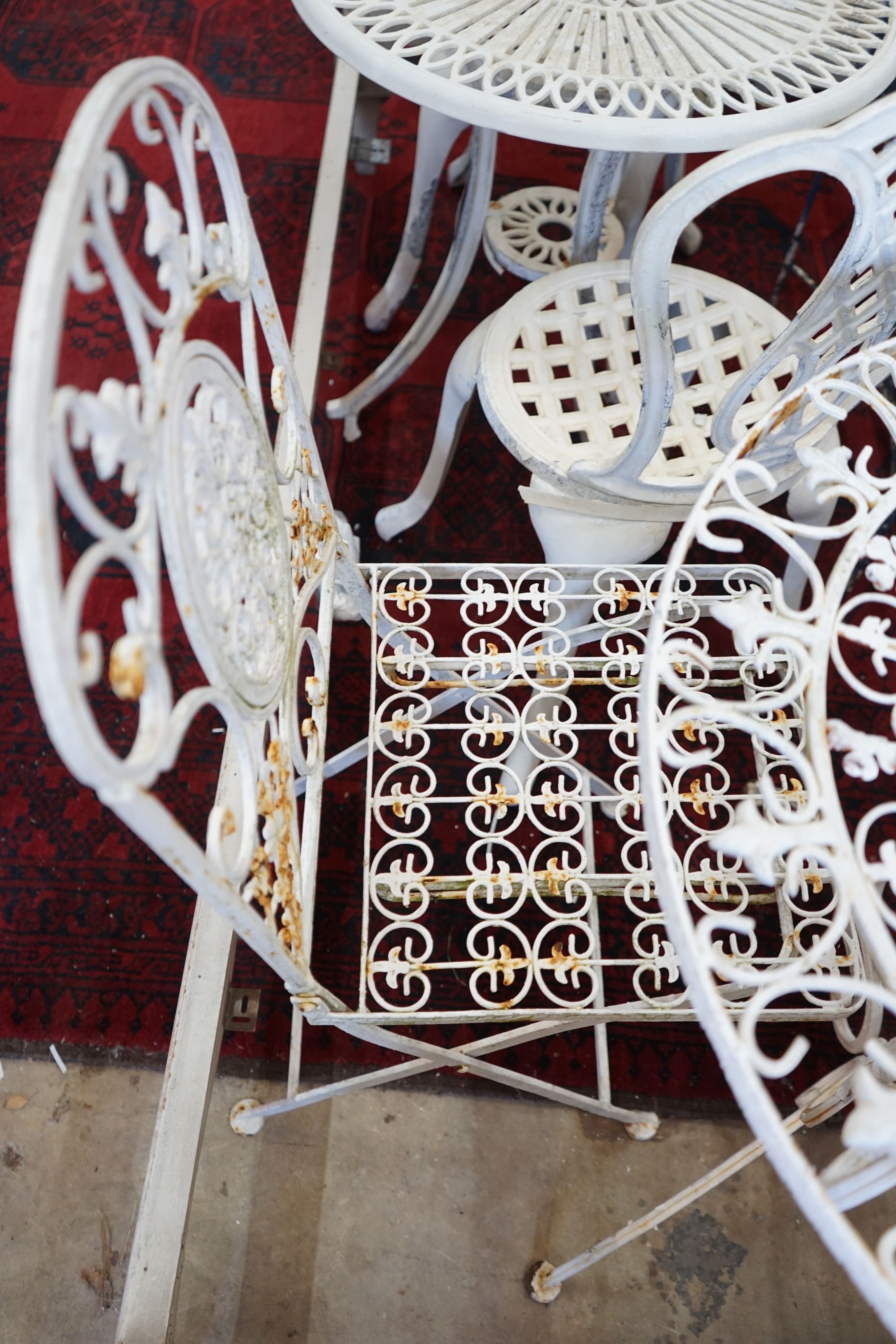 A painted circular metal garden table and 2 folding chairs, table 70 cms diameter.